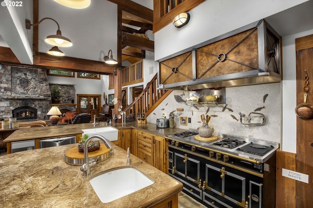 kitchen with backsplash, light stone counters, sink, and a fireplace