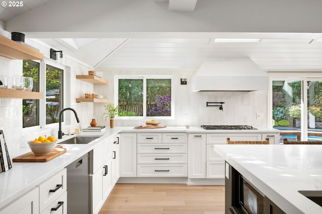 kitchen featuring premium range hood, a sink, decorative backsplash, light countertops, and gas stovetop