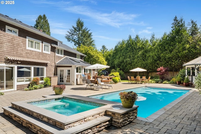 view of swimming pool with an in-ground hot tub, french doors, a patio area, a fenced backyard, and outdoor dining area