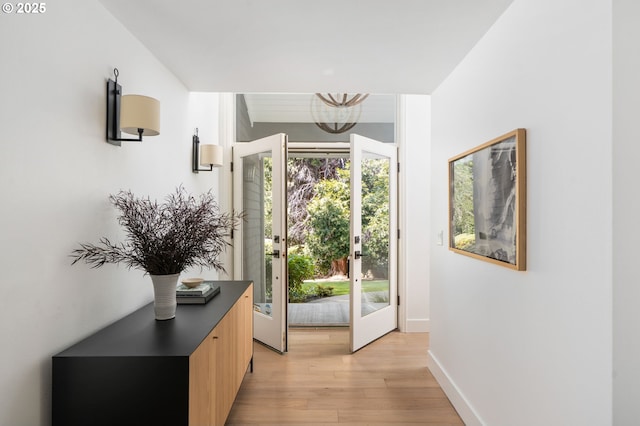 entrance foyer featuring light wood-style flooring, a chandelier, and baseboards