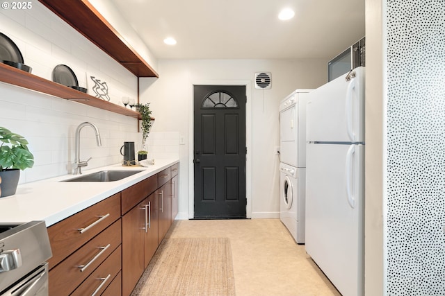 841 NE 77th Ave, Portland, OR 97213 - kitchen with freestanding refrigerator, stacked washer and clothes dryer, range, backsplash, and light countertops