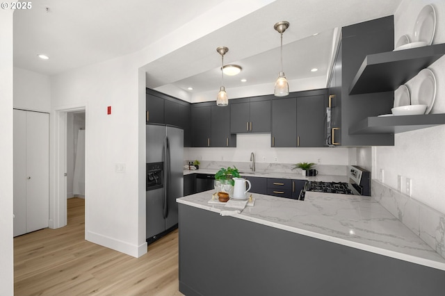 kitchen featuring hanging light fixtures, light hardwood / wood-style flooring, kitchen peninsula, stainless steel fridge, and range