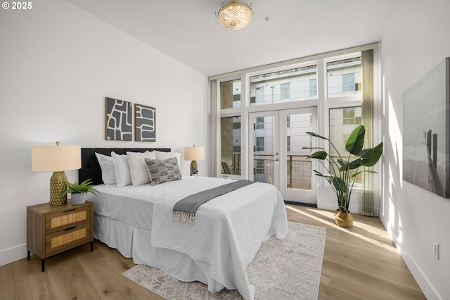 bedroom with expansive windows, access to exterior, wood-type flooring, and french doors