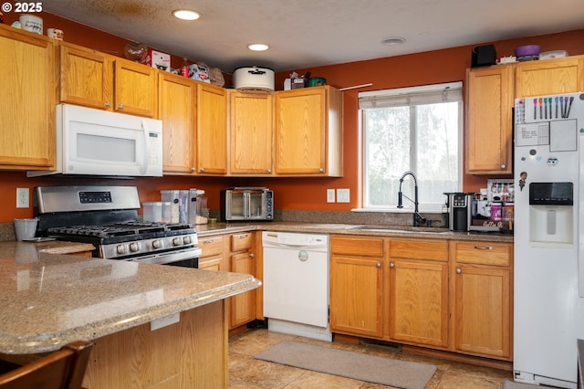 3052 Tierra Dr, Salem, OR 97305 - kitchen featuring a sink, recessed lighting, white appliances, a peninsula, and light stone countertops