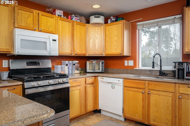 3052 Tierra Dr, Salem, OR 97305 - kitchen with light tile patterned floors, white appliances, light stone counters, and a sink