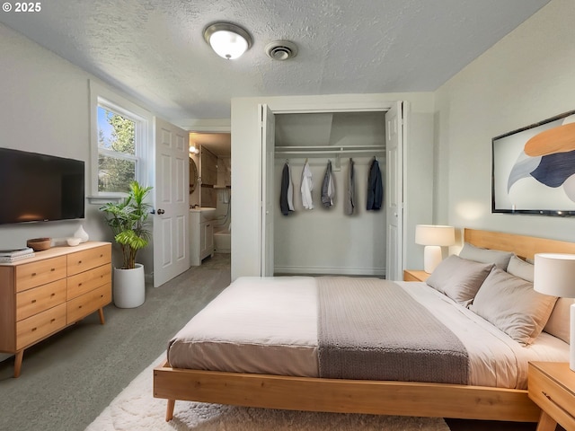 bedroom with a textured ceiling, ensuite bathroom, light carpet, visible vents, and a closet