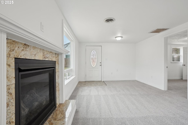 entryway featuring baseboards, a tiled fireplace, visible vents, and light colored carpet