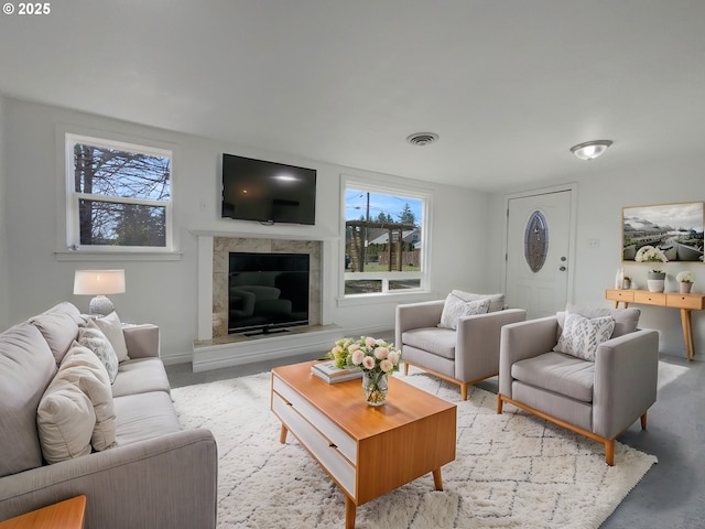 living area with a high end fireplace, visible vents, and baseboards