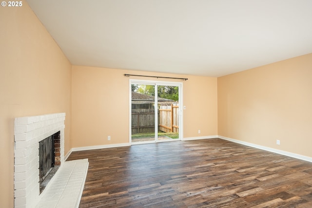 unfurnished living room with dark wood-style flooring, baseboards, and a fireplace
