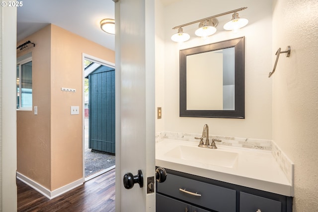 bathroom with baseboards, wood finished floors, and vanity