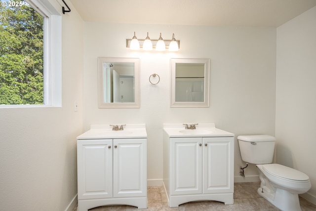bathroom with a sink, baseboards, toilet, and two vanities