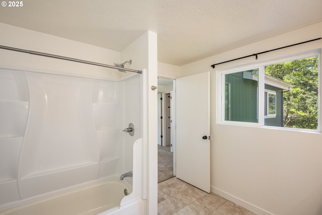 bathroom with tile patterned flooring, a textured ceiling, washtub / shower combination, and baseboards