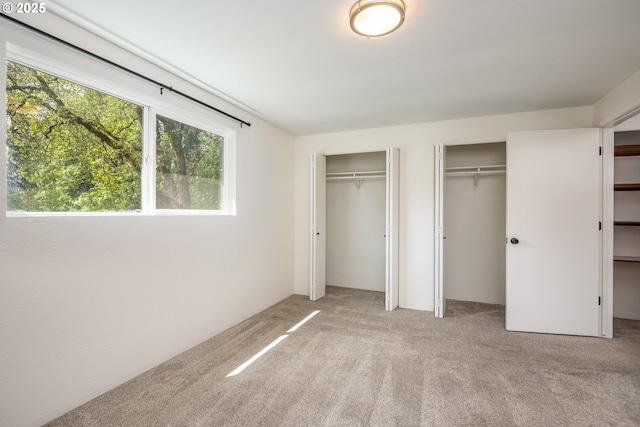 unfurnished bedroom with carpet flooring and two closets