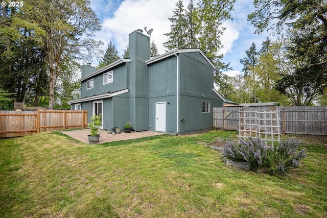 back of property with a yard, a chimney, a fenced backyard, and a patio area