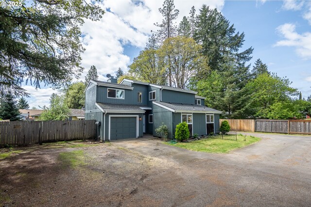 view of front facade with fence, roof with shingles, a garage, a front yard, and driveway