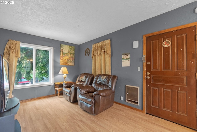 living room featuring a textured ceiling, wood finished floors, and baseboards