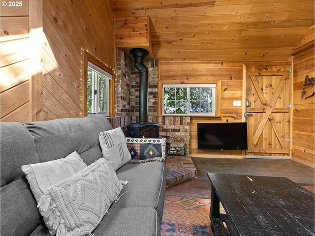 living area with wooden walls, vaulted ceiling, wooden ceiling, and a wood stove