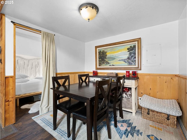 dining area with wooden walls, wood finished floors, and a wainscoted wall