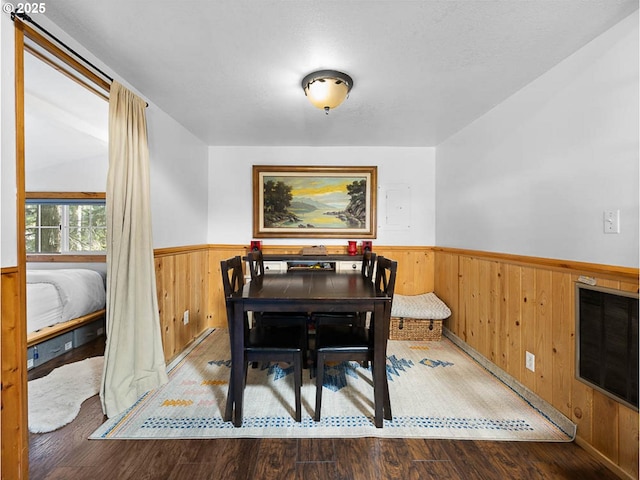 dining area featuring wooden walls, wainscoting, and wood finished floors