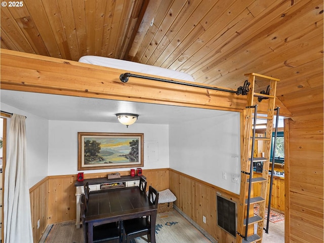 dining area featuring wooden walls, wood finished floors, wood ceiling, and a wainscoted wall