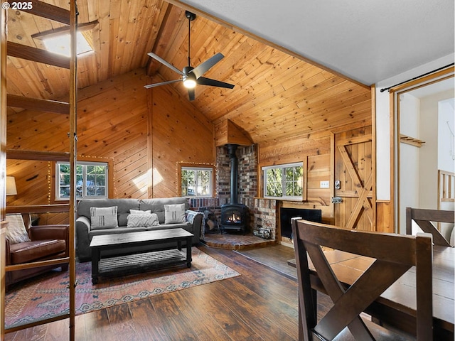 living area with a wood stove, wood walls, wood finished floors, wood ceiling, and a ceiling fan
