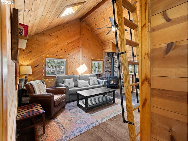 living area with wooden walls, wooden ceiling, a wood stove, and wood finished floors
