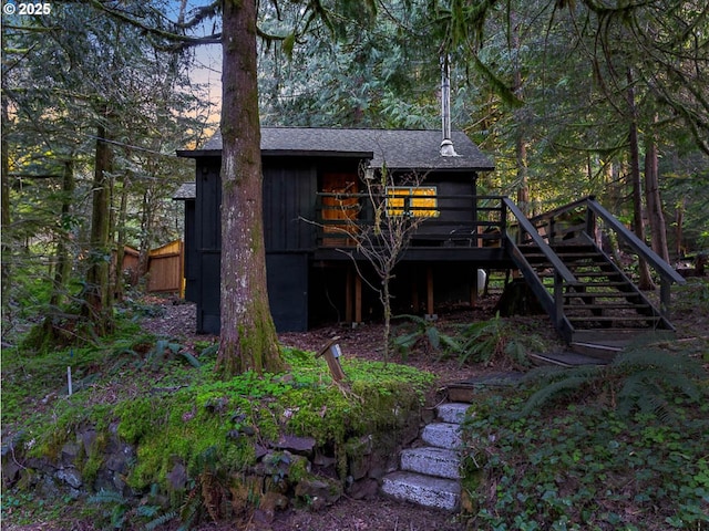 exterior space featuring a shingled roof, a wooden deck, and stairs