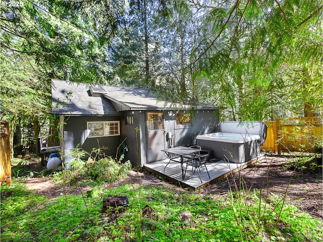 rear view of property featuring a fenced backyard and a hot tub