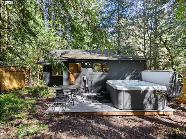exterior space featuring a hot tub, fence, and a deck