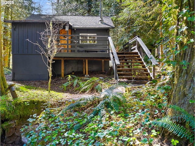 back of property featuring a shingled roof, a wooden deck, board and batten siding, and stairway