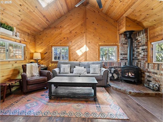 living room with a wood stove, lofted ceiling, wood walls, and hardwood / wood-style floors