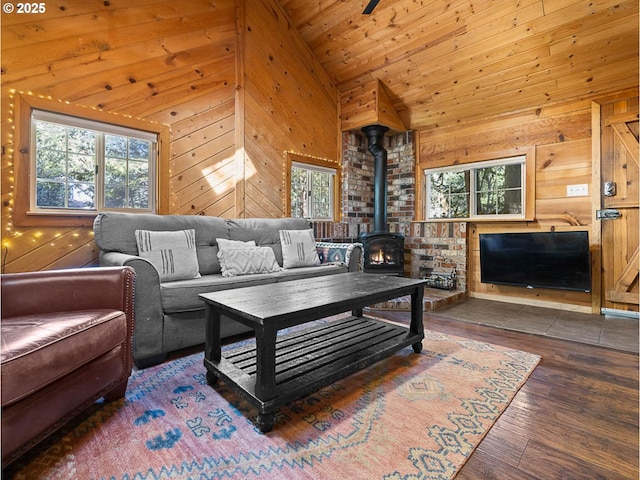 living room featuring wood finished floors, a wood stove, lofted ceiling, and wood walls