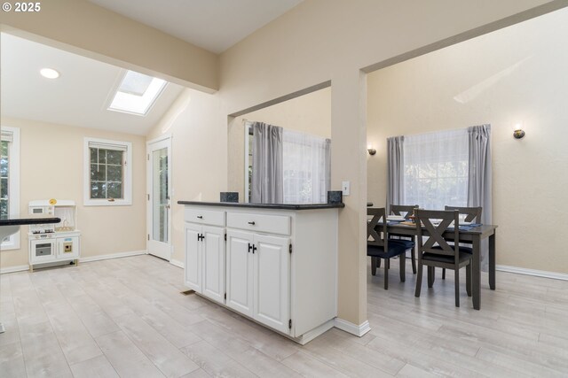 playroom with vaulted ceiling with skylight and light hardwood / wood-style floors