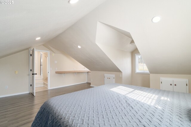 bedroom featuring multiple windows, light hardwood / wood-style floors, a textured ceiling, and lofted ceiling