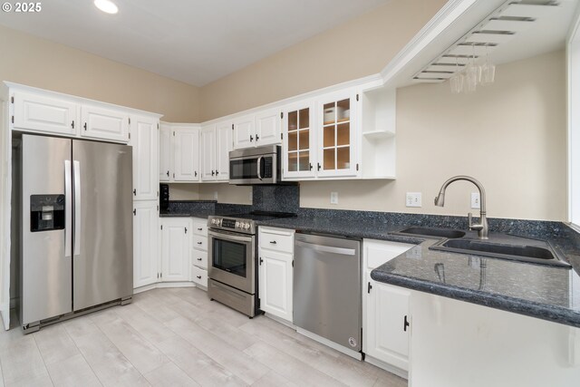 kitchen with sink, white cabinetry, light wood-type flooring, appliances with stainless steel finishes, and kitchen peninsula