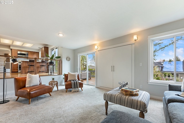 living room with light colored carpet, baseboards, and a healthy amount of sunlight