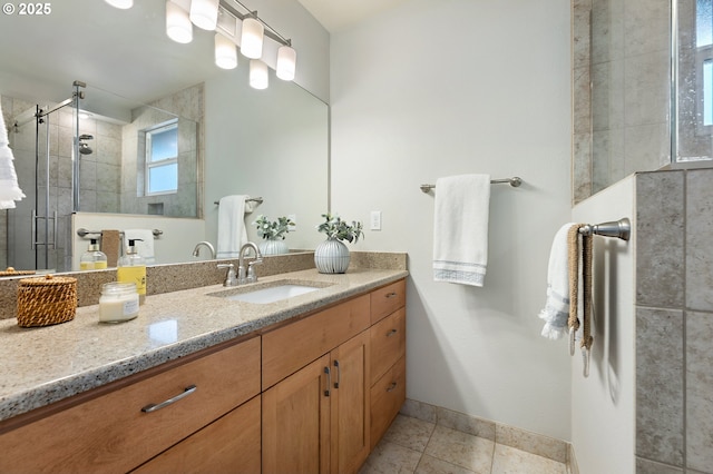 bathroom featuring tile patterned floors, tiled shower, vanity, and baseboards