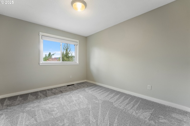 unfurnished room with carpet flooring, visible vents, and baseboards