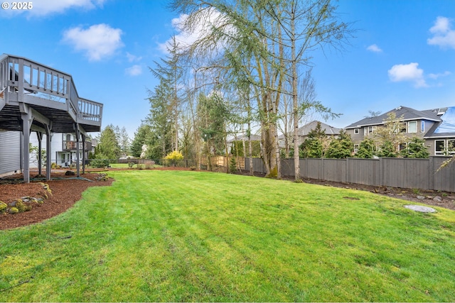 view of yard with a wooden deck, a fenced backyard, and stairs