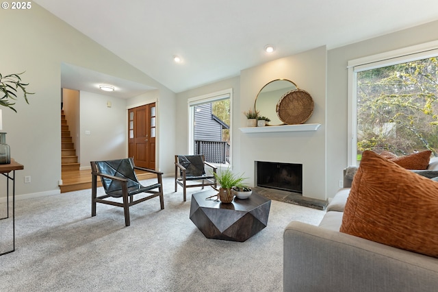 living area featuring carpet floors, lofted ceiling, a fireplace, stairs, and a wealth of natural light