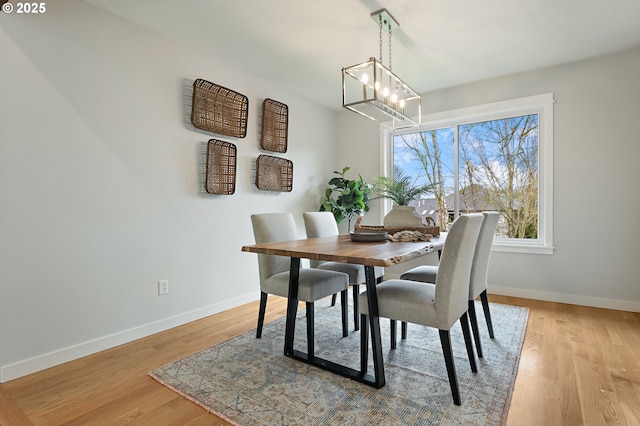 dining room with an inviting chandelier, light wood-style flooring, and baseboards