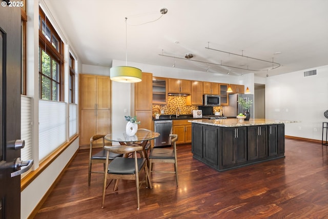 2350 NW Savier St Unit 100, Portland, OR 97210 - kitchen with stainless steel appliances, a center island, dark wood-type flooring, decorative backsplash, and glass insert cabinets