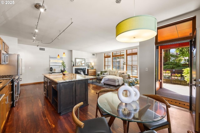 2350 NW Savier St Unit 100, Portland, OR 97210 - kitchen featuring dark wood-style flooring, stainless steel gas stove, pendant lighting, light stone countertops, and a center island