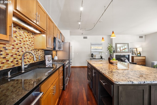 2350 NW Savier St Unit 100, Portland, OR 97210 - kitchen featuring stainless steel appliances, decorative backsplash, dark wood finished floors, light stone countertops, and a center island