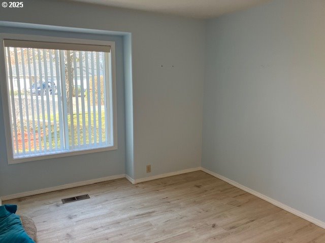 spare room featuring visible vents, a healthy amount of sunlight, and wood finished floors