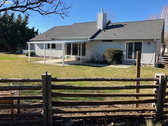 back of property featuring a patio, fence, a lawn, and a chimney