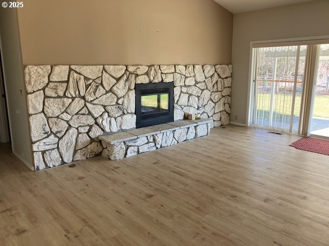 unfurnished living room with visible vents, a fireplace, and wood finished floors