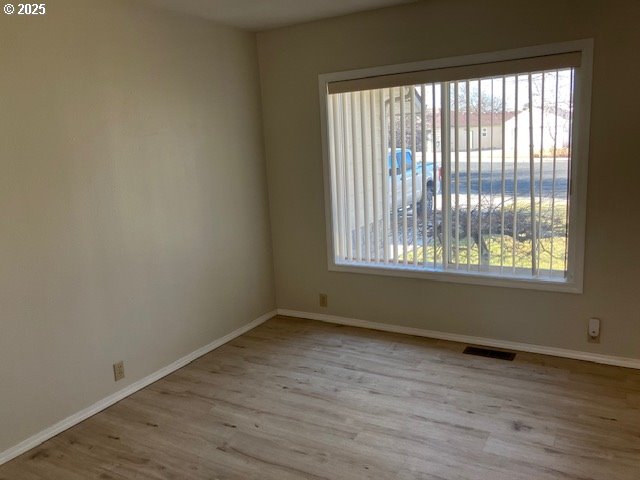 spare room with visible vents, baseboards, and wood finished floors