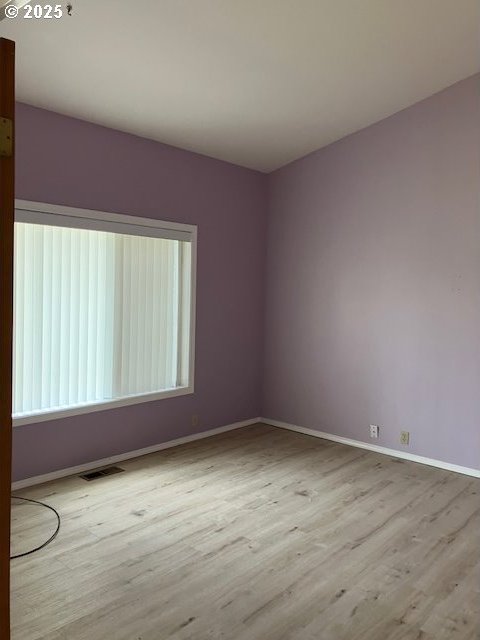 spare room featuring visible vents, baseboards, and wood finished floors