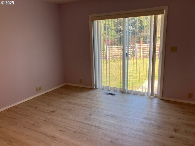 spare room with visible vents, baseboards, and wood finished floors